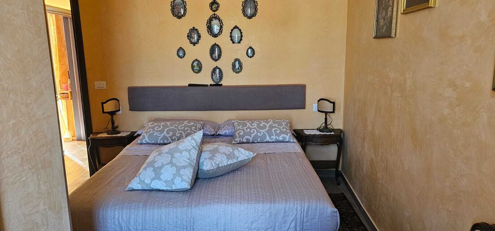 Een bed met beddengoed met een patroon, een hoofdbord, nachtlampjes en spiegels aan de muur.