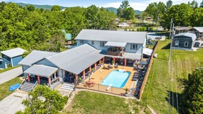 A large house with a swimming pool, covered outdoor seating, and a fenced patio area.