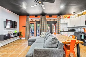 A modern kitchen with white cabinets, a dining table, and orange chairs. - FUN TIMES LUXURY RESORT-3BD/2BA-LAKEFRONT-POOL-ARCADE-PLAYAREA-DOG AREA-MARINA (Jacksboro)