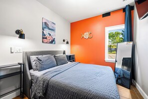 Un dormitorio moderno con cama, mesitas de noche, un cuadro y una ventana con cortinas.