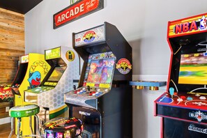 Eine Reihe von Spielautomaten, darunter Street Fighter II und NBA Jam, vor einer Holzwand.