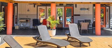 Ein zweistöckiges Haus mit überdachter Terrasse, Sitzgelegenheiten im Freien und einem Swimmingpool.