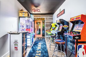 Ein Flur mit Spielhallenspielen, einem Tischtennis-Tisch und einer Tür zu einem Zimmer.