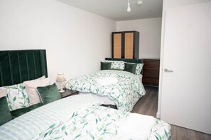A bedroom with two beds, a wardrobe, and a door. - Beautifully designed 1 bedroom apartment (Eccles)