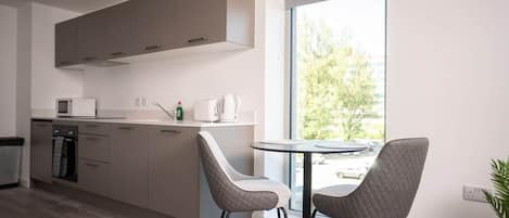 A modern kitchen with a dining area, a large window, and a view of the outdoors.