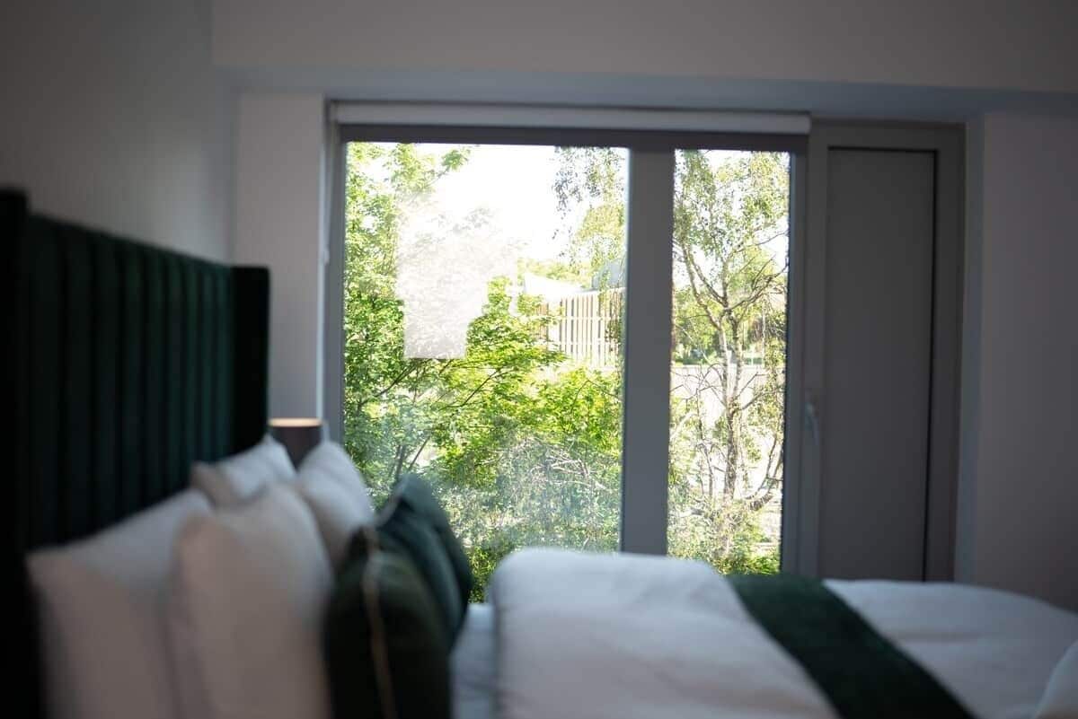 A bedroom with a bed, a window, and a view of greenery outside.
