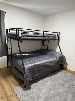 Ein Stockbett in einem Raum mit Holzboden und grauem Teppich.
