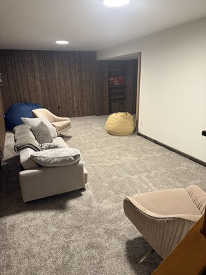 Ein Zimmer mit einem beige gefärbten Sofa, einem blauen Sitzsack und einem gelben Sitzsack.