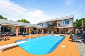 Ein zweistöckiges Gebäude mit Swimmingpool, Außenbereich zum Sitzen und einer überdachten Terrasse.