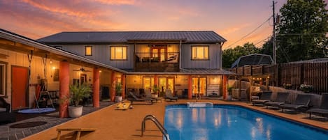Un edificio de dos pisos con piscina, mobiliario exterior y un patio cubierto.