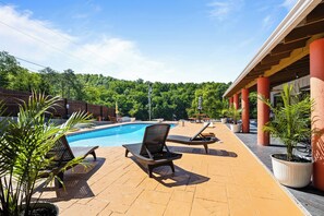 Ein Poolbereich mit Liegestühlen, einem Schwimmbecken und einer überdachten Terrasse mit Pflanzkübeln.