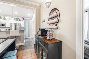 A modern kitchen with a coffee station, a dining area with a bench, and a view of the living room. - FUN TIMES LUXURY RESORT-3BD/2BA-LAKEFRONT-POOL-ARCADE-PLAYAREA-DOG AREA-MARINA (Jacksboro)