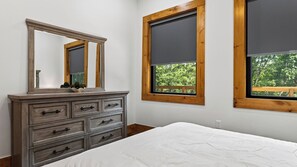 A bedroom with a wooden dresser, a bed, and two windows with wooden frames. - Spurling Retreat by Avantstay Sleeps 20 + Indoor Pool + Game Room Near Pigeon Forge (Sevierville)