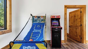 A room with a basketball arcade game, a basketball hoop, and a wooden door. - Spurling Retreat by Avantstay Sleeps 20 + Indoor Pool + Game Room Near Pigeon Forge (Sevierville)