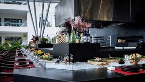 Uma área de bar moderna com balcão longo, gelo e diversos copos e garrafas.