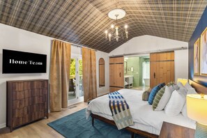 A bedroom with a bed, a TV, a wardrobe, and a sliding door to a bathroom. - Starry Skies: Sauna, S'mores & Pickleball Retreat (Blue Ridge)