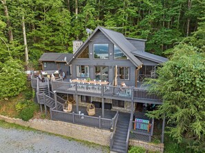 Eine zweistöckige Lodge mit Balkon und Außenbereich, umgeben von Wald.