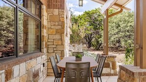 Une terrasse extérieure avec des murs en pierre, une table en bois et des chaises en osier.