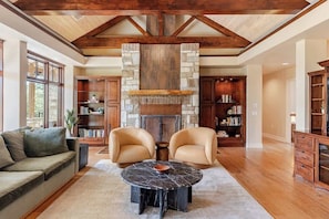 A spacious living room with a stone fireplace, leather armchairs, and a marble coffee table. - Luxury Estate Spa Bathroom, Observation Deck, Pool (Driftwood)