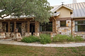 A stone house with a covered porch and large windows. - Luxury Estate Spa Bathroom, Observation Deck, Pool (Driftwood)