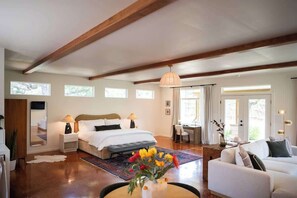 A bedroom with a bed, bedside tables, a desk, a chair, a sofa, and a window. - Boutique 1BR Retreat, chilled & heated cowboy pool (Driftwood)