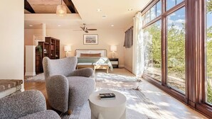 Ein Schlafzimmer mit einem Bett, einem Sessel, einem runden Tisch und einem großen Fenster.