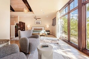 Ein Schlafzimmer mit einem Bett, einem Sessel, einem runden Tisch und einem großen Fenster.