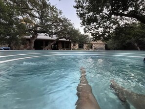 A swimming pool with a view of a building and trees in the background. - Boutique Hill Country Estate with viewing turret (Driftwood)