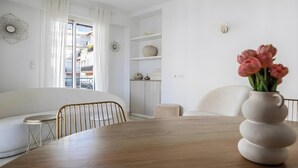 Un salon moderne avec une table à manger en bois, des canapés blancs et un vase rempli de fleurs.