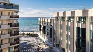 Un immeuble à plusieurs étages doté de balcons donnant sur une plage et la mer.