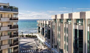 Ein mehrstöckiges Gebäude mit Balkonen mit Blick auf Strand und Meer.