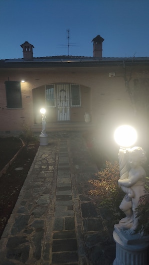 A building with a stone pathway leading to a gated entrance, two chimneys, and a statue on the right. - Nice room, bathroom, outdoor space for the summer. Highway, airport, hospitals (Madone)