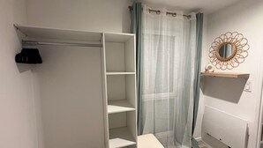Een badkamer met inloopkast, douchegordijn, spiegel en radiator.