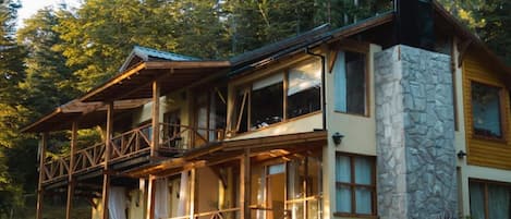 A two-story lodge with a stone facade, wooden balconies, and a porch area.