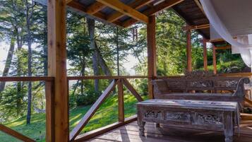 Une terrasse en bois avec un banc, entourée d’arbres.