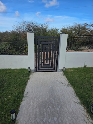 A gated entrance with a geometric design, a paved pathway, and two lantern-style lights. - Welcome to Modern Maison 

Tranquil studio apartment located in beautiful Nevis (Nevis)