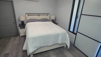 A bedroom with a bed, bedside tables, a ceiling light, a wardrobe, and a door.