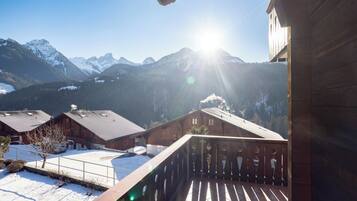 Un bâtiment en bois doté d’un balcon donnant sur un paysage enneigé et des montagnes.