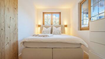 Ein Schlafzimmer mit Bett, Nachttischlampen, einem Fenster mit Bergblick und einer Holzwand.