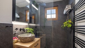 A modern bathroom with a large mirror, a stone sink, a wooden cabinet, and a towel rack. - Unique Chalet, Mountain View, Terrace, Gstaad (Château-d’Œx)