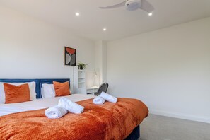 A hotel room with a bed, a desk, a chair, and a ceiling fan. - Family Friendly 4 Bedroom House in Rayleigh (Essex)