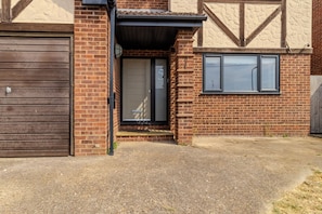 A residential building with a garage, a front door, and a window. - Family Friendly 4 Bedroom House in Rayleigh (Essex)