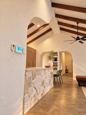 A modern kitchen with a stone island, wooden beams, and a ceiling fan. - The Bale @ Quindalup. Secluded 4-bedroom bushland retreat on Quindalup Hill (Quindalup)