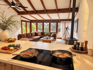 A modern kitchen with a stove, a pan of food, and a large window. - The Bale @ Quindalup. Secluded 4-bedroom bushland retreat on Quindalup Hill (Quindalup)