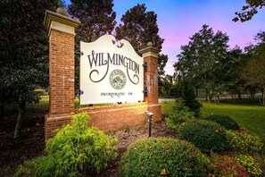 A sign for Wilmington, Incorporated, with a brick wall and greenery around it. - Brooklyn Arts Condo | Walk to Live Oak & Dining (Wilmington)