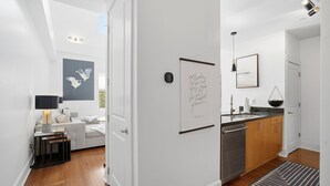 A modern interior with a living area, kitchen, and a hallway. - Brooklyn Arts Condo | Walk to Live Oak & Dining (Wilmington)