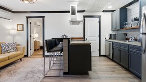Cocina moderna con una isla central, electrodomésticos integrados y una zona de comedor con sofá y sillas.