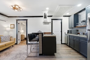 Eine moderne Küche mit Kochinsel, integrierten Geräten und einem Essbereich mit Sofa und Stühlen.