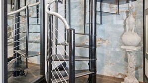 Un interior moderno con una escalera de caracol, paredes de mármol y una estatua.