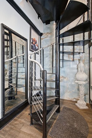 Ein modernes Interieur mit einer Wendeltreppe, Marmorwänden und einer Statue.